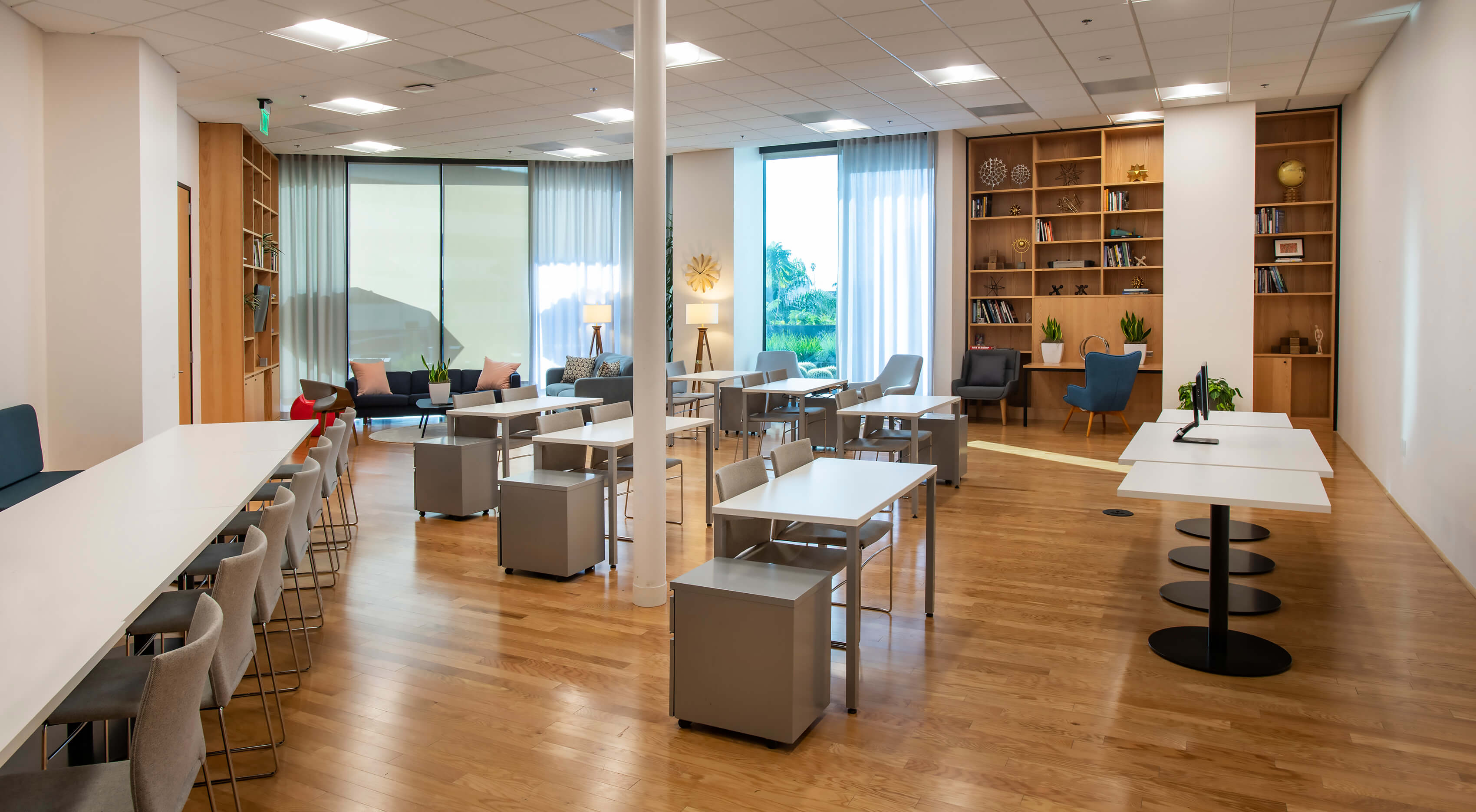 Full view of the Meeting Hall at 1800 Vine St showing communal tables, lounge seating, and bookshelves