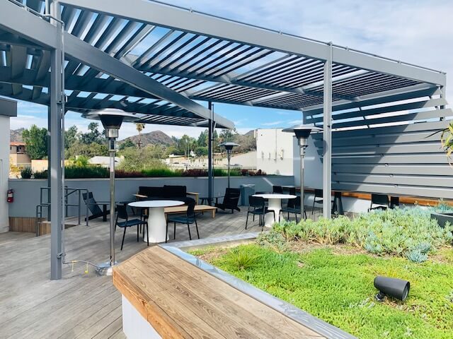 Terrace furniture and patio heaters under the louvered pergola at 1800 Vine St