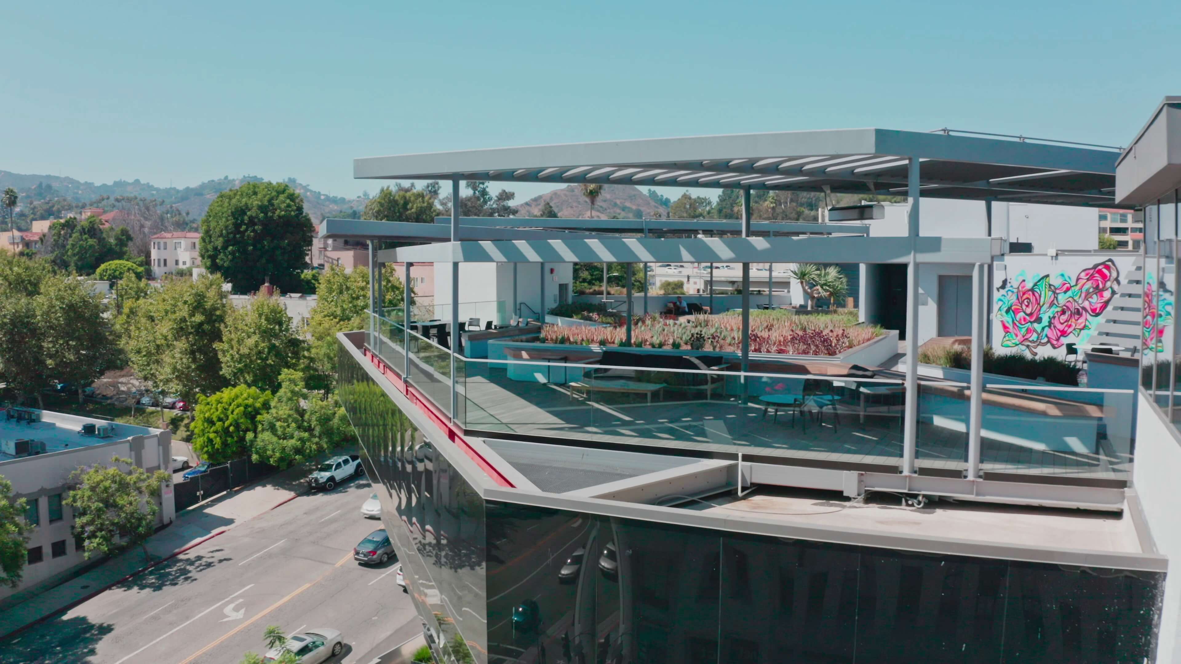 Open-air rooftop terrace with pergola shading and mural art at 1800 Vine St